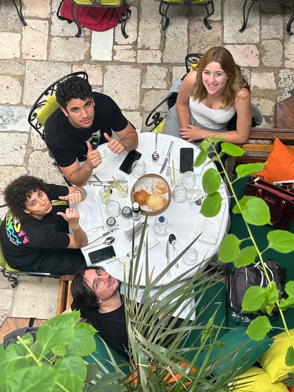 Des personnes réunies autour d’une table extérieure, près de plantes.