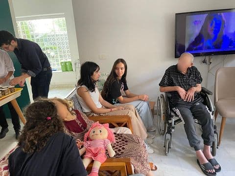 Des personnes assises ensemble dans une pièce, près d’un téléviseur.