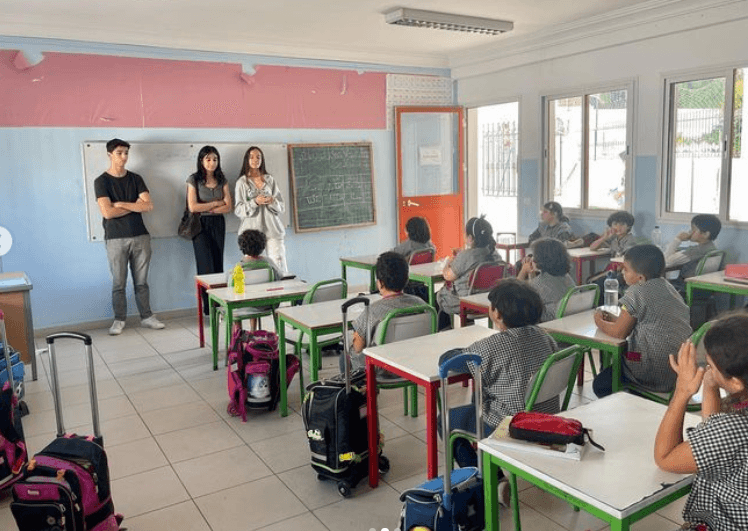 Des personnes s’adressant à des élèves assis dans une salle de classe.