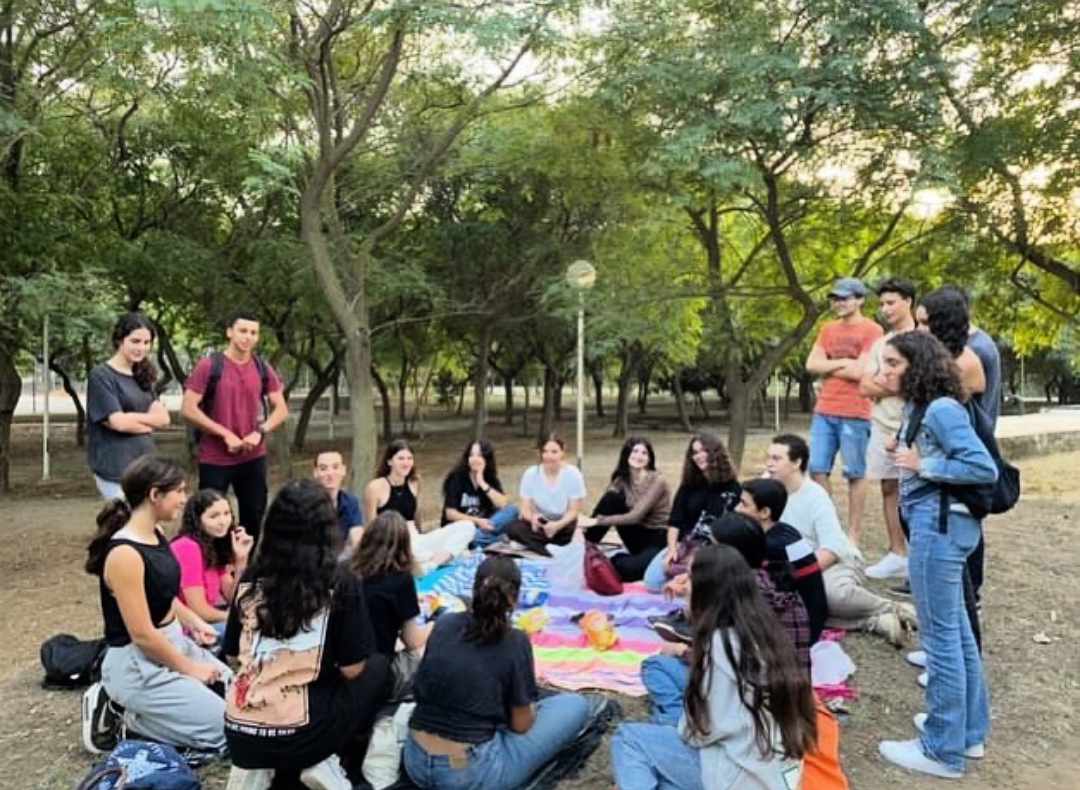 Un groupe réuni autour d’une table de pique-nique, sous les arbres.