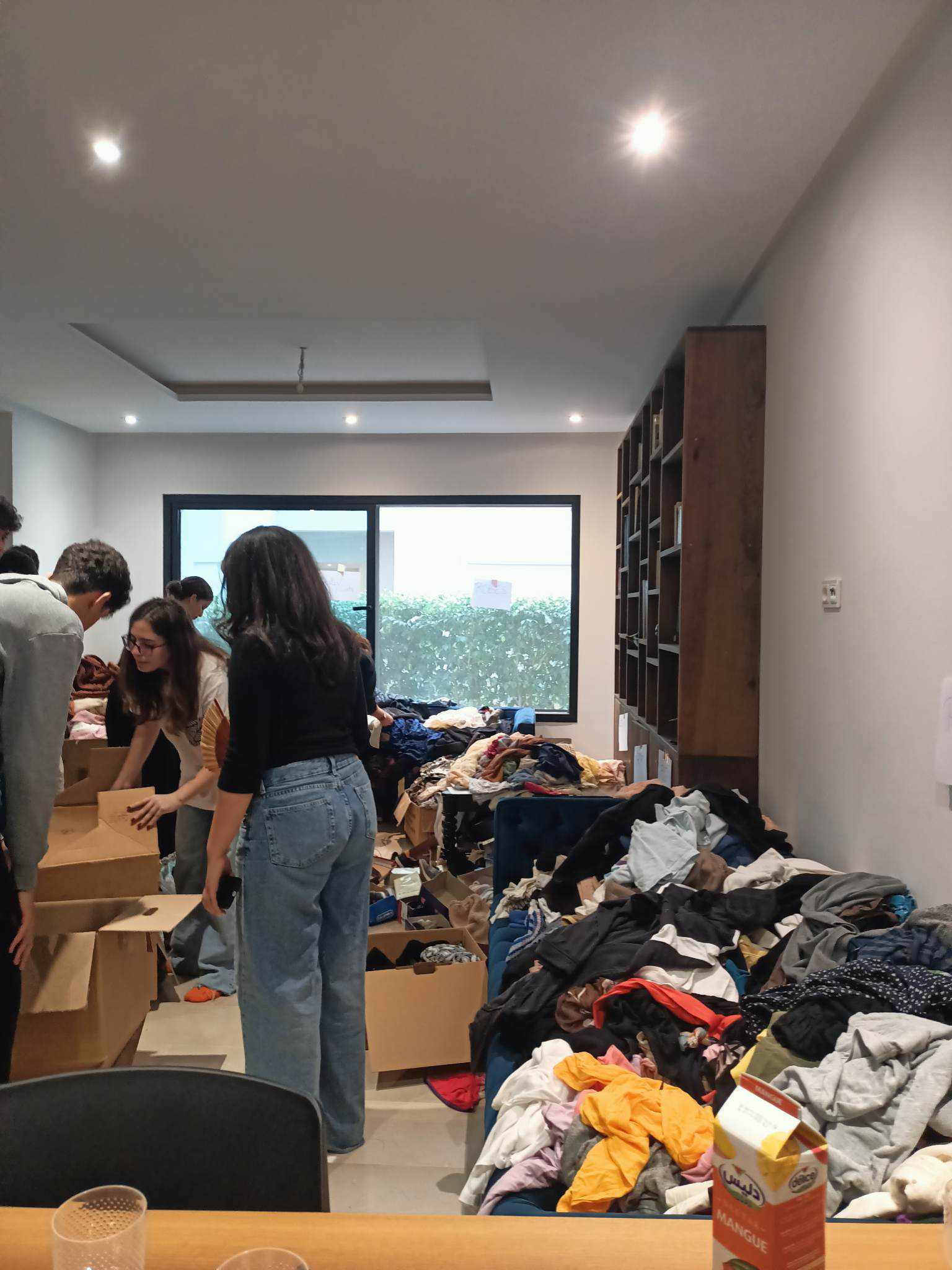 Des personnes triant des vêtements et des cartons dans une pièce.