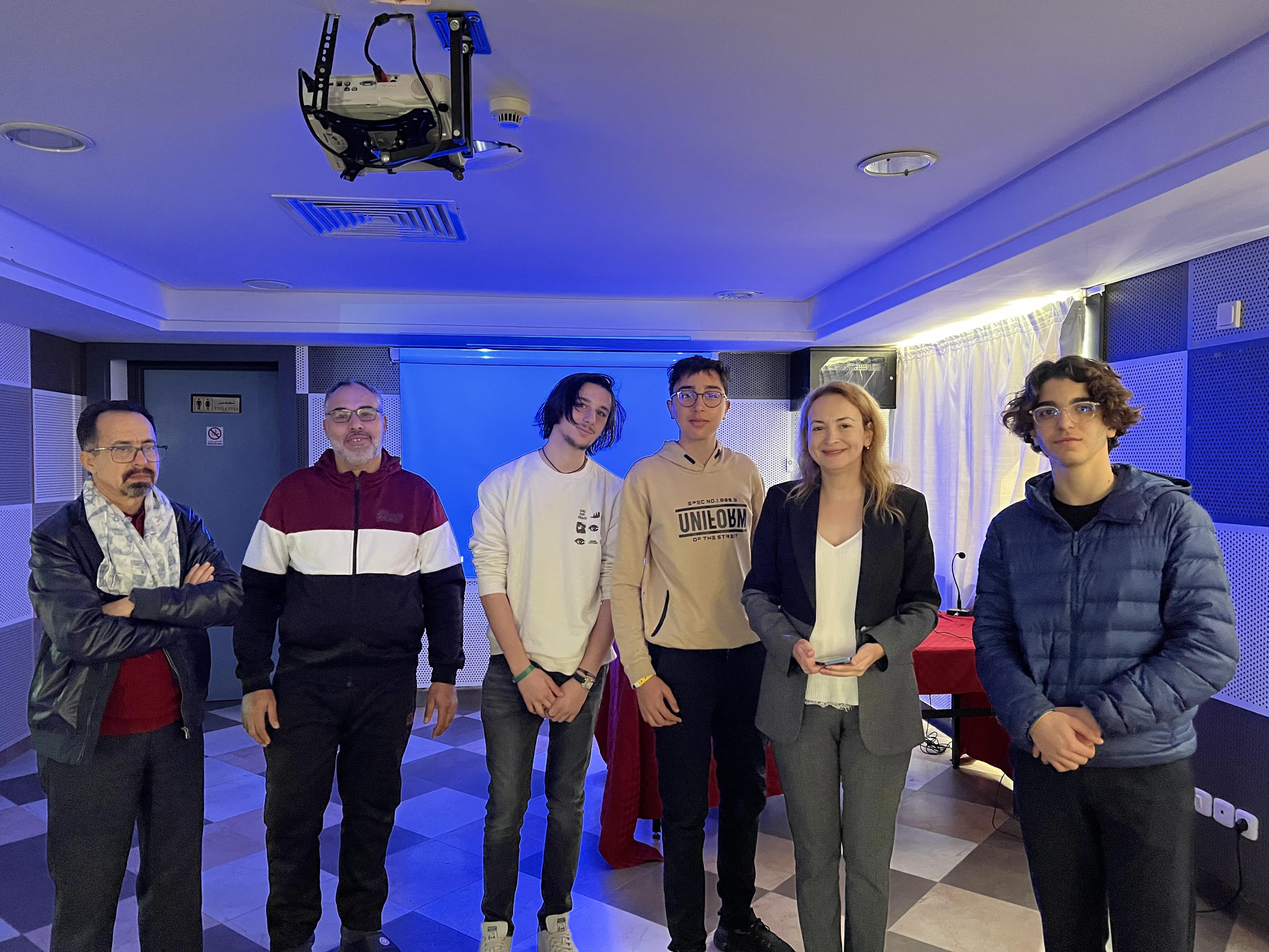 Un groupe prenant la pose dans une pièce éclairée en bleu.
