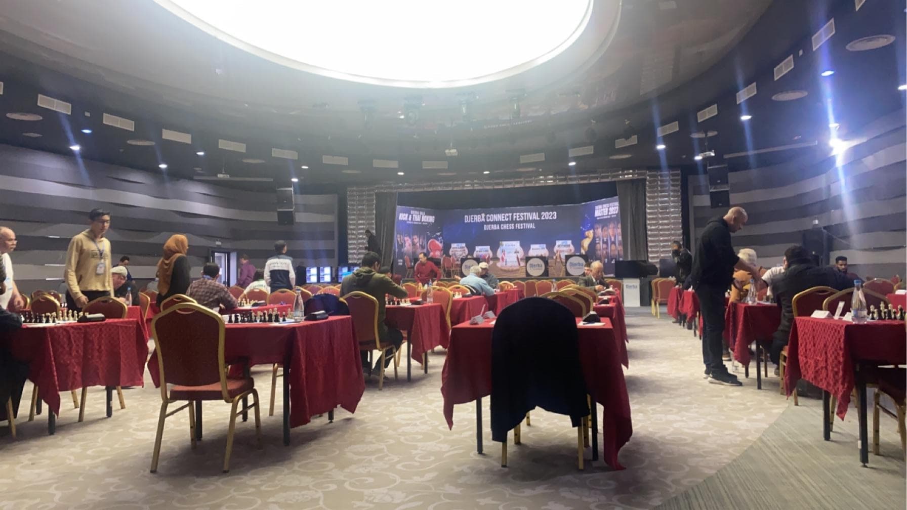 Des rangées de tables et de chaises équipées d’échiquiers dans une grande salle.