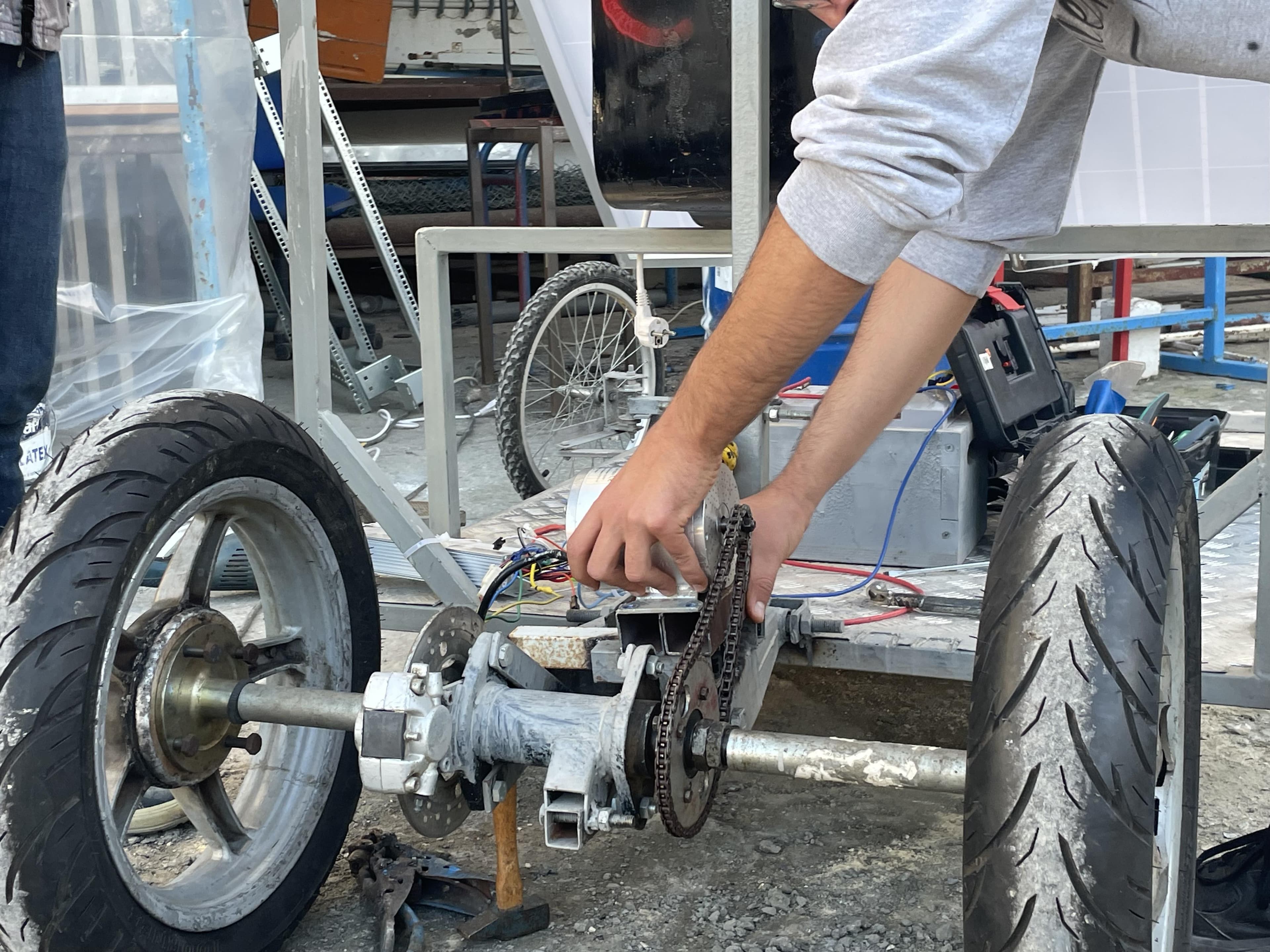 Close-up of hands working beside the chain drive, rear axle and wheels