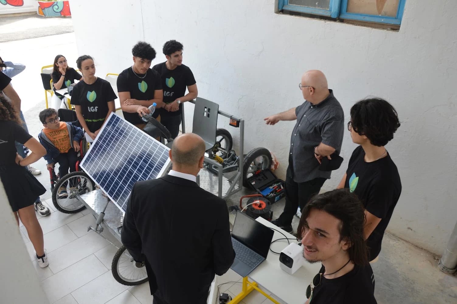Des personnes autour de la voiture électrique solaire, avec un ordinateur portable à côté du prototype
