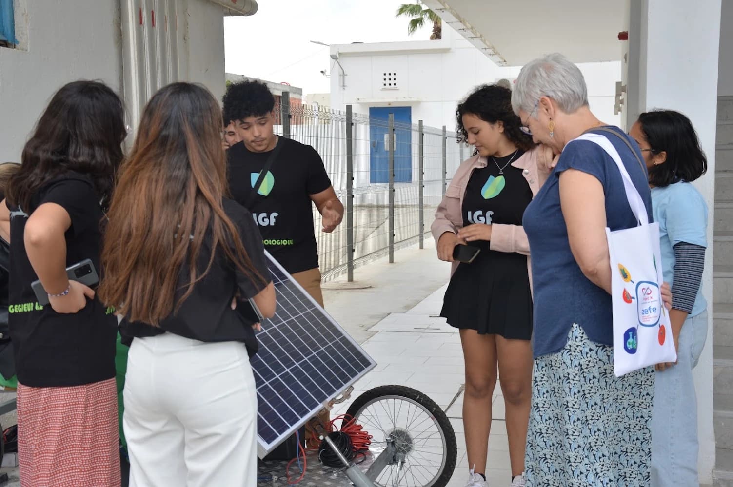 Un groupe réuni autour du panneau solaire et de la roue avant du prototype de véhicule