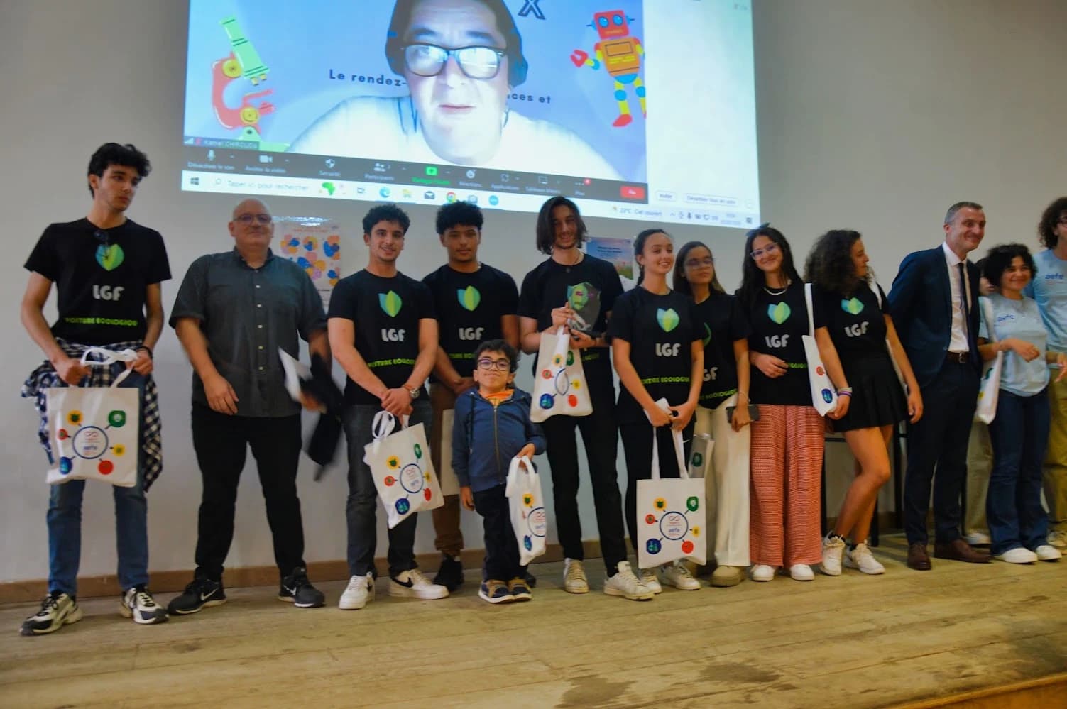 Un groupe sur une scène avec un trophée en verre et des sacs Projet X